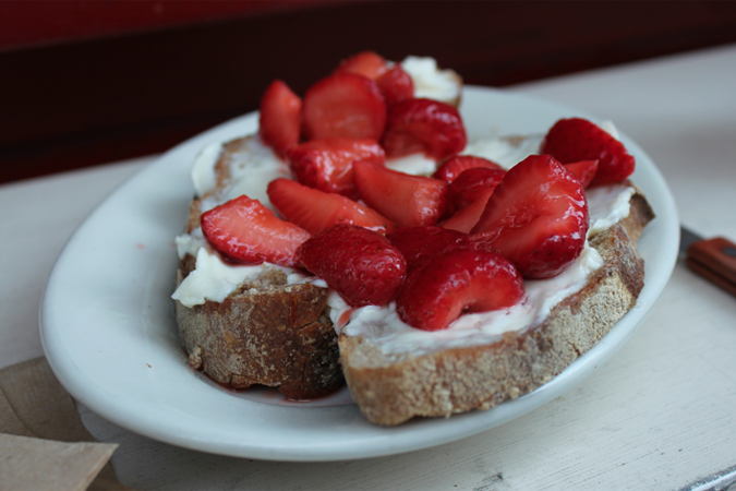 Fresh strawberries on top of mascarpone cheese and a multigrain loaf.